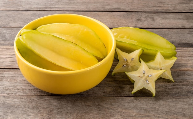 Starfruits met plakjes in een kom over houten tafel