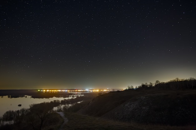 街と森の夜の星空。長時間露光の風景。