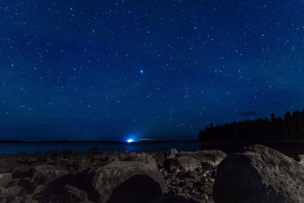 Starry sky with constellations galaxies milky way and many stars above water of river with stones