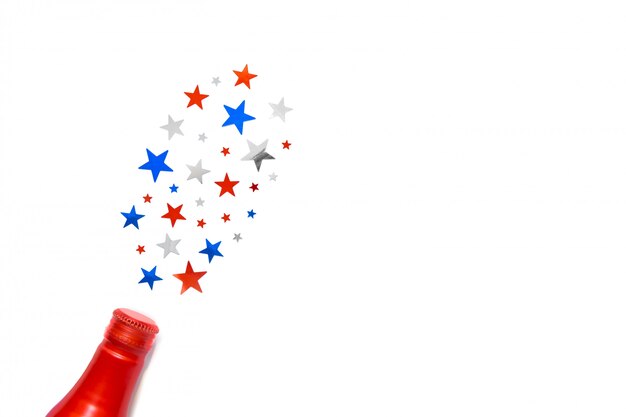 Stars confetti in color of american flag fly out the bottle isolated on white backdrop. Space for text. Fourth of july. Decor for independence day of America.