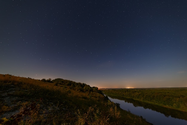 Stars in the night sky over the river. Illuminated by moonlight. Photographed with a long exposure.