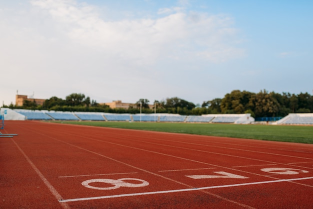 Start line for running on stadium, nobody, front view. Empty treadmill with numbers, injury-proof coating, jogging surface on sport arena