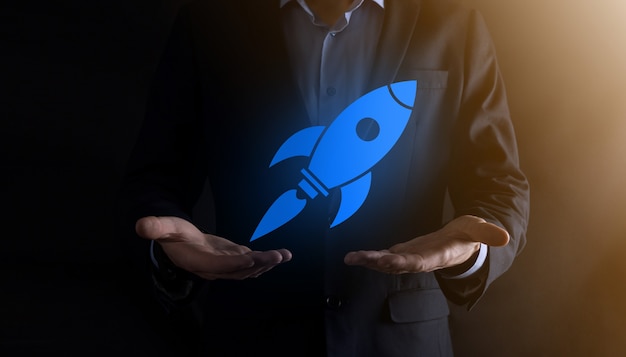 Start up concept with businessman holding abstract digital rocket icon rocket is launching and soar flying.