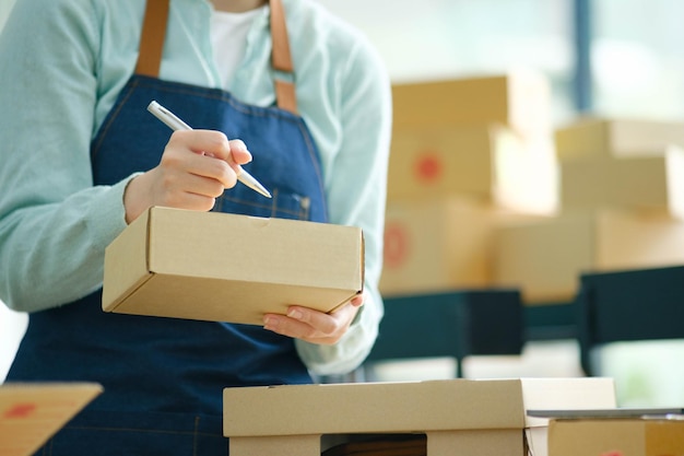 Start up small business owner writing address on cardboard box a