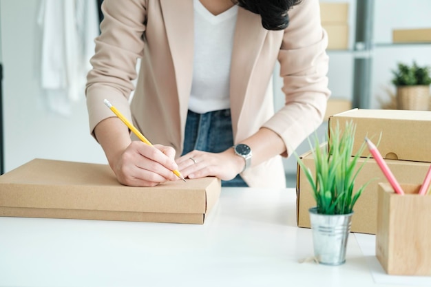 Start up small business owner writing address on cardboard box a