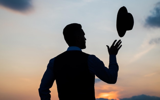 Start your day here. personal achievement goal. man with hat\
silhouette on sky. confident businessman throw hat. daily\
motivation. enjoying life and nature. business success. carefree\
and freedom.