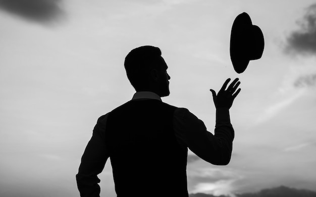 Inizia la tua giornata qui obiettivo di realizzazione personale uomo con silhouette cappello sul cielo uomo d'affari fiducioso gettare cappello motivazione quotidiana godersi la vita e la natura successo aziendale spensierata e libertà