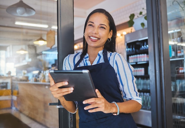 Startcafé en zakenvrouw in management met een glimlach die op een digitale tablet in de winkel werkt Manager coffeeshop-eigenaar of werknemer van een klein bedrijf aan het werk in de detailhandel met technologie