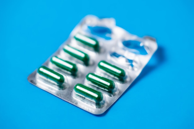 Started packing of tablets with green capsules Blue background background Probiotics vitamins concept