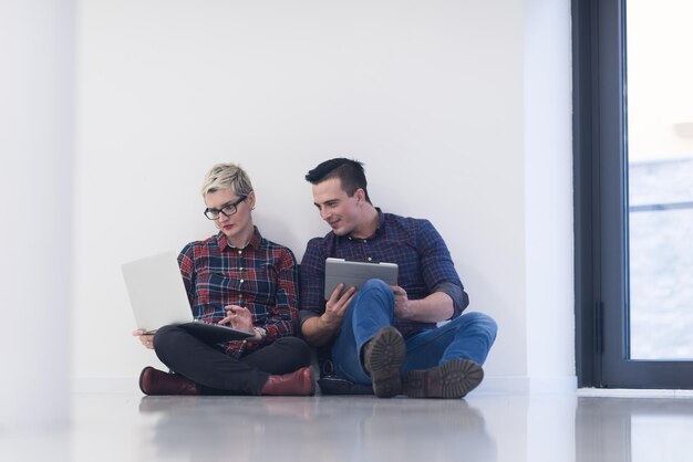 startend bedrijf en nieuw concept voor mobiele technologie met jong stel in modern licht kantoorinterieur dat werkt op laptop en tabletcomputer aan nieuw creatief project en brainstormen