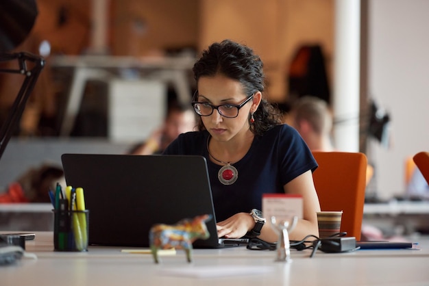 startend bedrijf, vrouw die werkt op laptopcomputer op modern kantoor