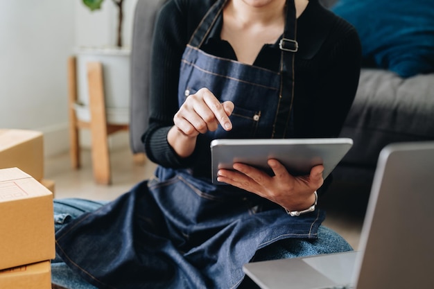 Startende mkb-bedrijfseigenaar die digitale tablet gebruikt om de bestelling te controleren van de online aankooporder van de klant