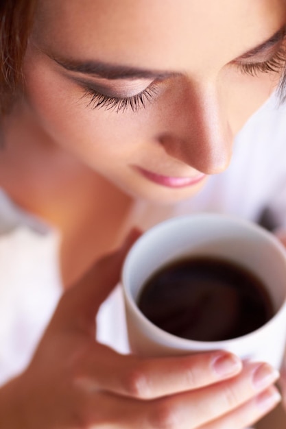 淹れたてのコーヒーで一日を始める朝のコーヒーを飲みながら思慮深く見える若い女性