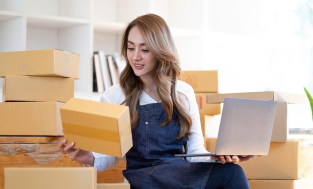 Starting a small business SME owner female entrepreneurs are using the rope to tie boxes to pack products Order online to prepare to pack a box of goods for sale to customers sme business idea