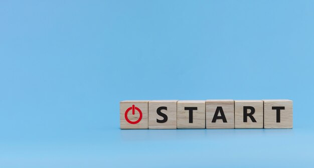 Startknop. woord START geschreven op houten kubusblokstapel op blauwe achtergrond, nieuwjaarsfelicitatie, idee, financiën, strategie, opstarten van een bedrijf, online marketing, doel en doelplanconcept