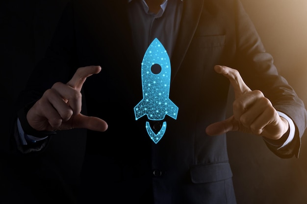 Startup business concept, Businessman holding in hand icon rocket is launching and soar flying out from screen with network connection on dark background.Low poly,polygonal.Profit, rise, development