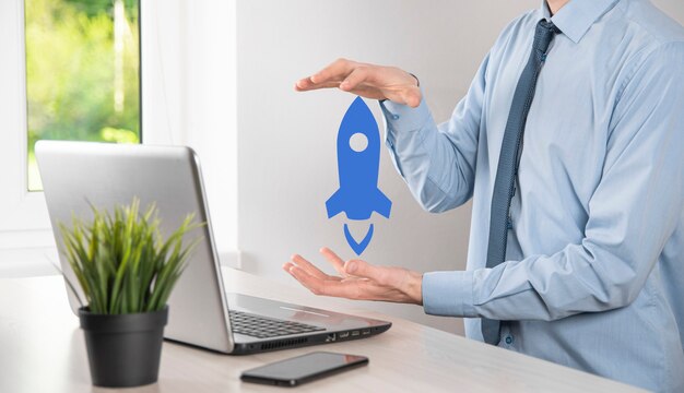 Startup business concept, Businessman holding tablet and icon rocket is launching and soar flying out from screen with network connection on dark background.