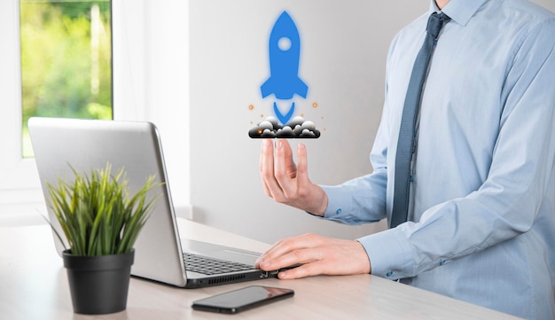 Startup business concept, Businessman holding tablet and icon rocket is launching and soar flying out from screen with network connection on dark background.