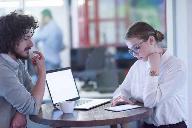 Avviare uomini d'affari che utilizzano il laptop che si preparano per la prossima riunione mentre bevono caffè e discutono di idee nell'ufficio creativo