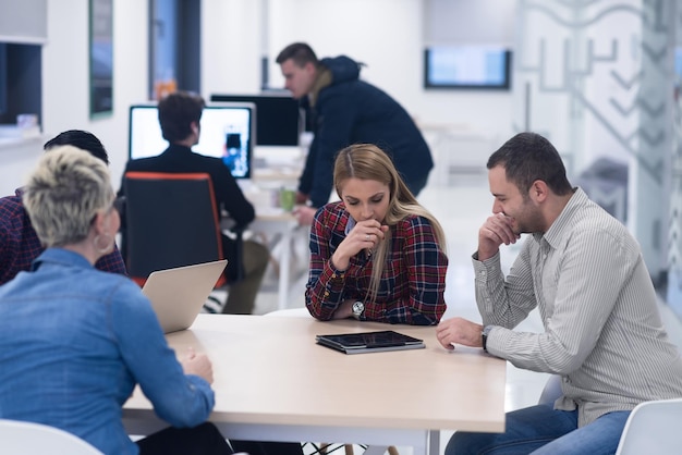 Startup business team bij het ontmoeten in een modern, helder kantoorinterieur brainstormen, werken op laptop en tabletcomputer