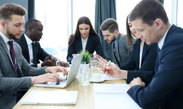 Startup business team on meeting in modern bright office interior and working on laptop.