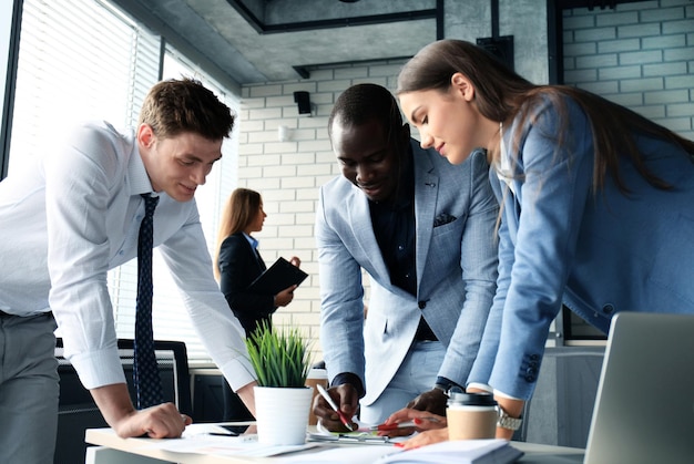 Foto startup business team op bijeenkomst in moderne, lichte kantoorinterieur brainstormen, werken op laptop en tabletcomputer.