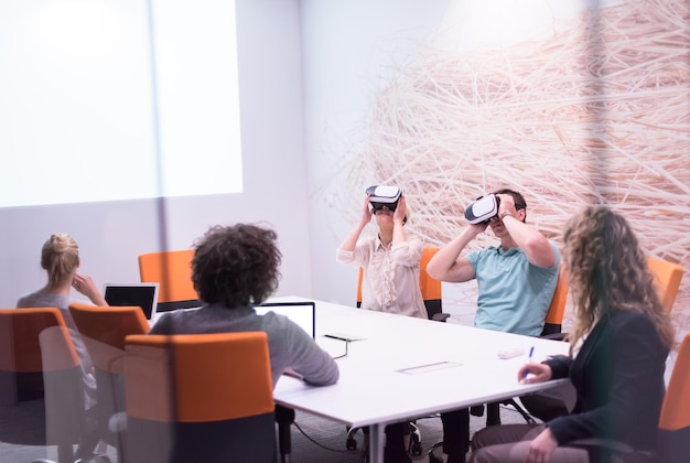 Startup business team using virtual reality headset in night\
office meeting developers meeting with virtual reality simulator\
around table in creative office.