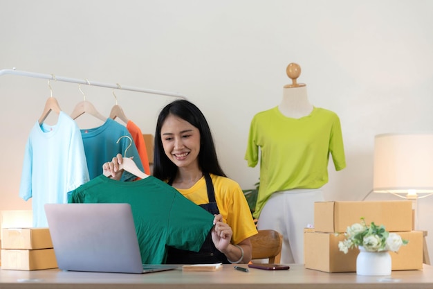 Photo startup small business entrepreneur sme asian woman packing cloth in box portrait young asian small business owner home office online sell marketing delivery sme ecommerce telemarketing concept