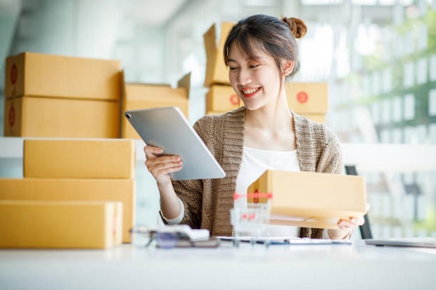 startup small business entrepreneur sme or freelance young asian woman using a laptop computer with box successful asian woman working online marketing packaging delivery sme online business ideas