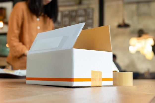 Startup small business woman owner packing cardboard box at workplace.