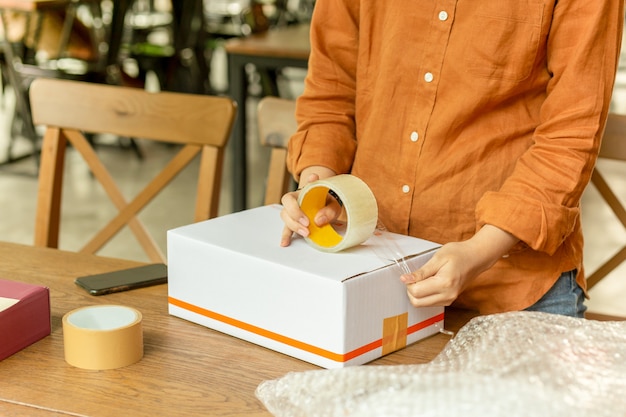 Startup small business woman owner packing cardboard box at workplace.