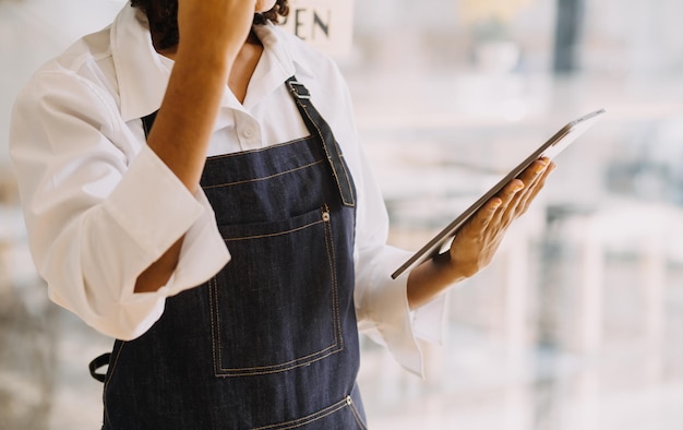 Startup succesvolle kleine ondernemer sme schoonheid meisje staan met tablet smartphone in koffie winkel restaurant portret van Aziatische bruine vrouw barista café eigenaar kmo ondernemer verkoper bedrijfsconcept