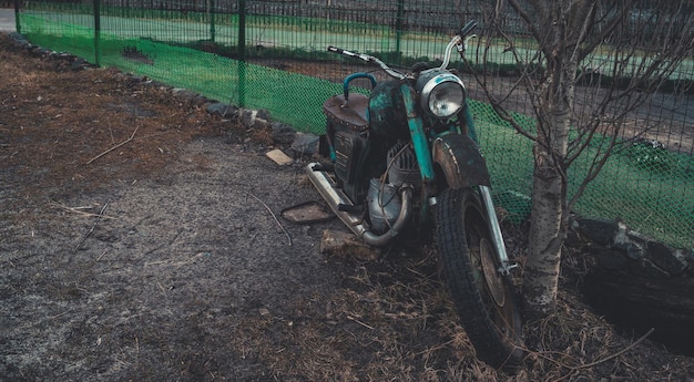 Старый Оскол, Россия, 25 января 2019 г. Старый ржавый мотоцикл возле забора на земле Закрыть брошенный сломанный мотоцикл