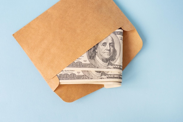 Stash di denaro in banconote da un dollaro che esce da una busta su sfondo blu il concetto di stipendio bustarella prestito debito vincere