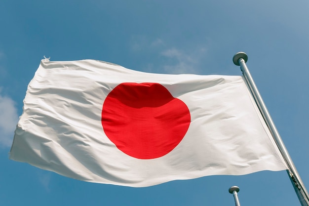 State Japanese flag on the strong wind over blue sky background