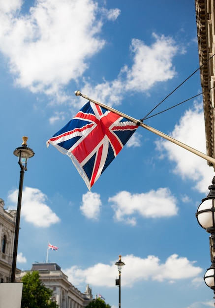 州のシンボルと国民の祝日のコンセプト – ロンドンの街に手を振るイギリスのニオン・ジャックの旗