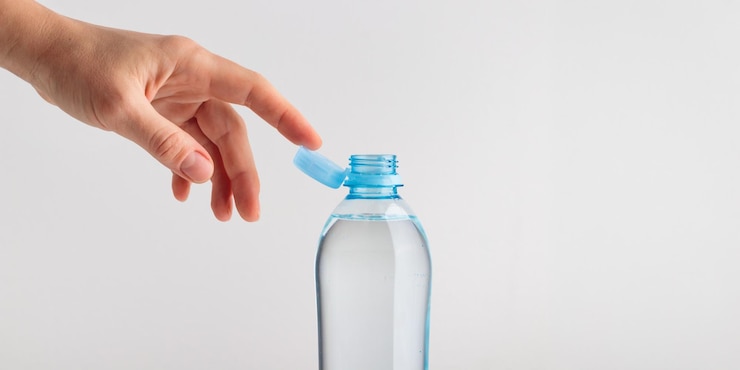Stationaire plastic dop op een PET-fles met menselijke hand Het nieuwe ontwerp betekent dat de dop na het openen aan de fles blijft bevestigd, waardoor de hele verpakking gemakkelijker te verzamelen en te recyclen is.