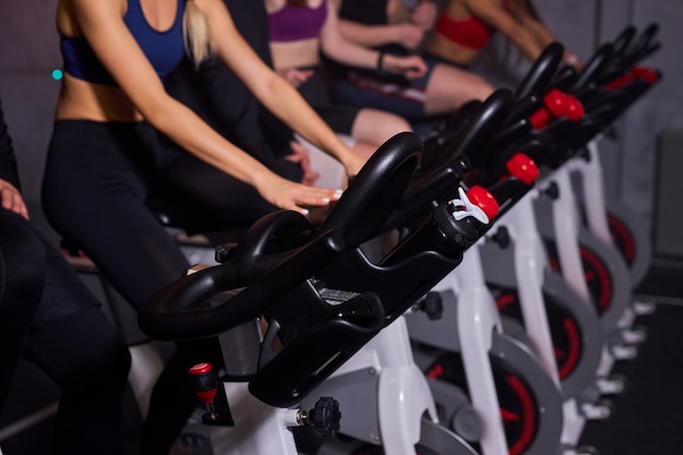 Stationary bicycles fitness people in a gym sport club, close-up hands of athlete people during working out