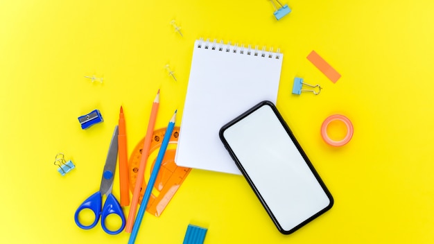 stationeries and phone on yellow background