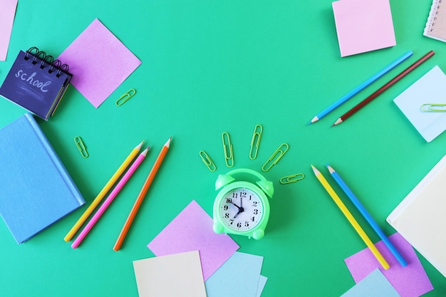 Stationery, alarm clock, books on a background of pastel colors paper, back to school, education