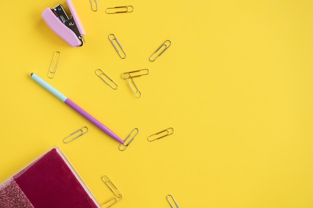 Foto gli elementi decorativi sono su sfondo giallo la penna e la cucitrice si trovano vicino alle graffette