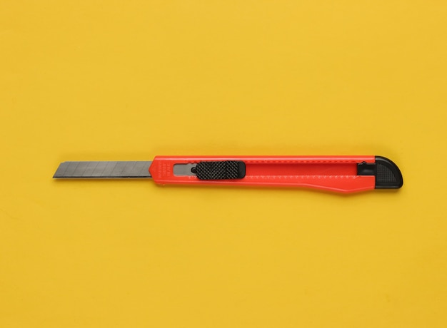 Stationery knife for cutting paper on yellow paper