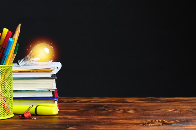 Stationery and light bulb with light on books with copy space