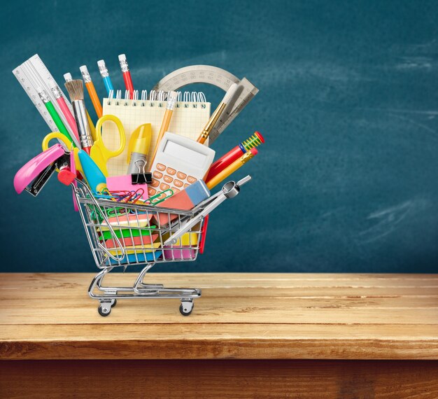 Stationery objects in mini supermarket cart on  background