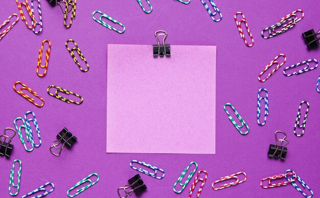 Stationery office supplies. Colored memo paper, paper clip on purple background.