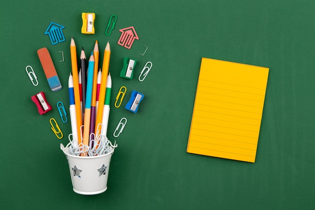 Stationery Pencils paper clip pen eraser in a white bucket. Still life on green school board background. Copy space Flat lay Top view Concept Education