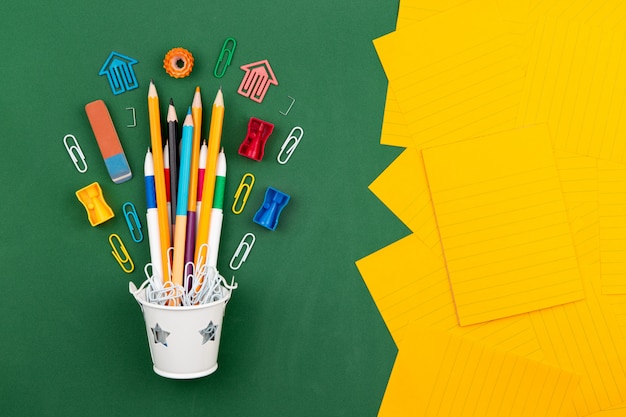 Stationery Pencils paper clip pen eraser in a white bucket. Still life on green school board background. Copy space Flat lay Top view Concept Education