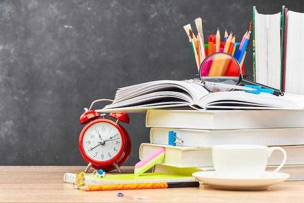 Stationery for school in a cart on the background of a blackboard