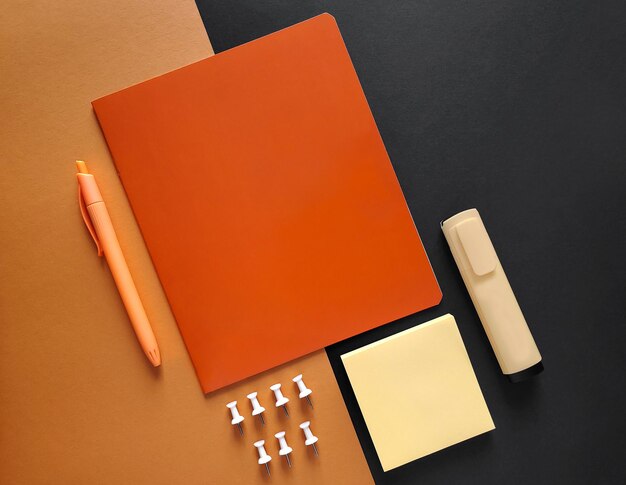 Stationery for school and office on black and orange background, top view