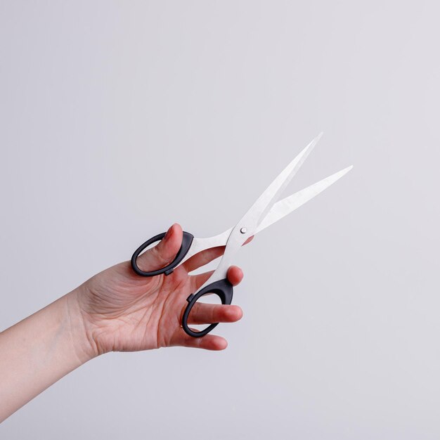 Фото Канцелярские ножницы в руке девушки на белом фоне. фото высокого качества